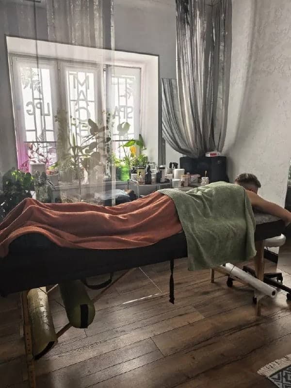 Кабинет днём: большое окно, живые растения и гость на массаже